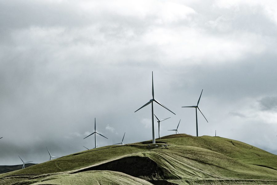 Wind turbines along a green ridgeline under heavy cloud