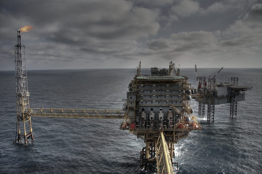 An offshore production platform under heavy cloud, flare stack at left