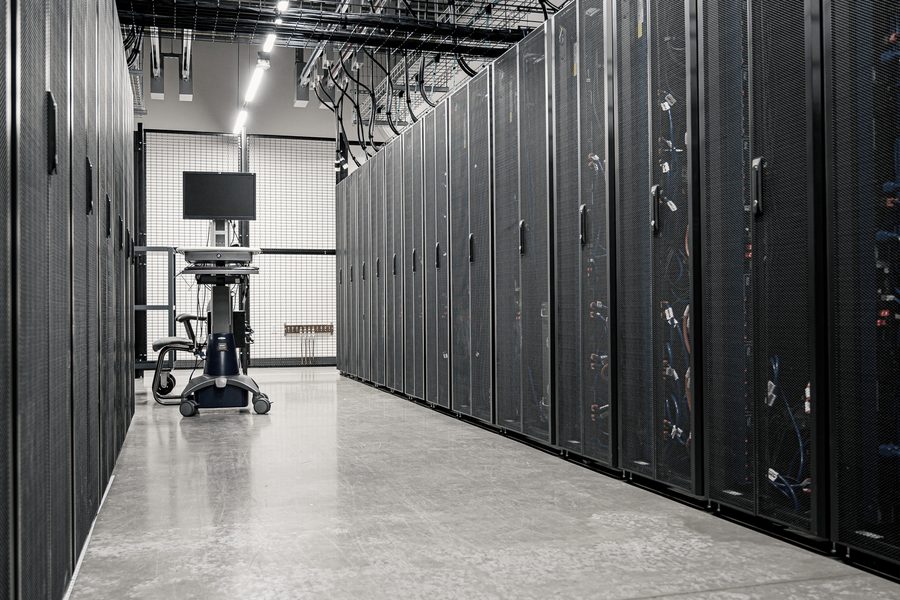 A data centre aisle, server racks and patch cabling receding into the distance