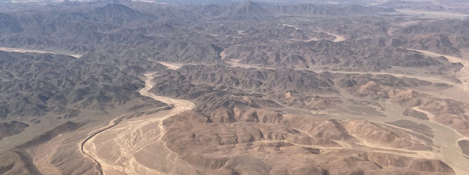 Aerial view of arid basin terrain cut by braided dry riverbeds