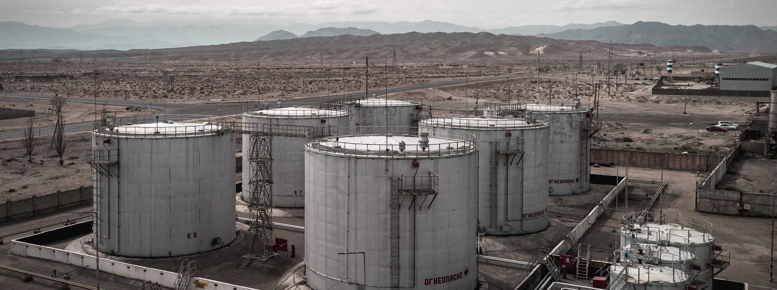 A tank farm on an arid plain, storage cylinders in a row below distant ranges